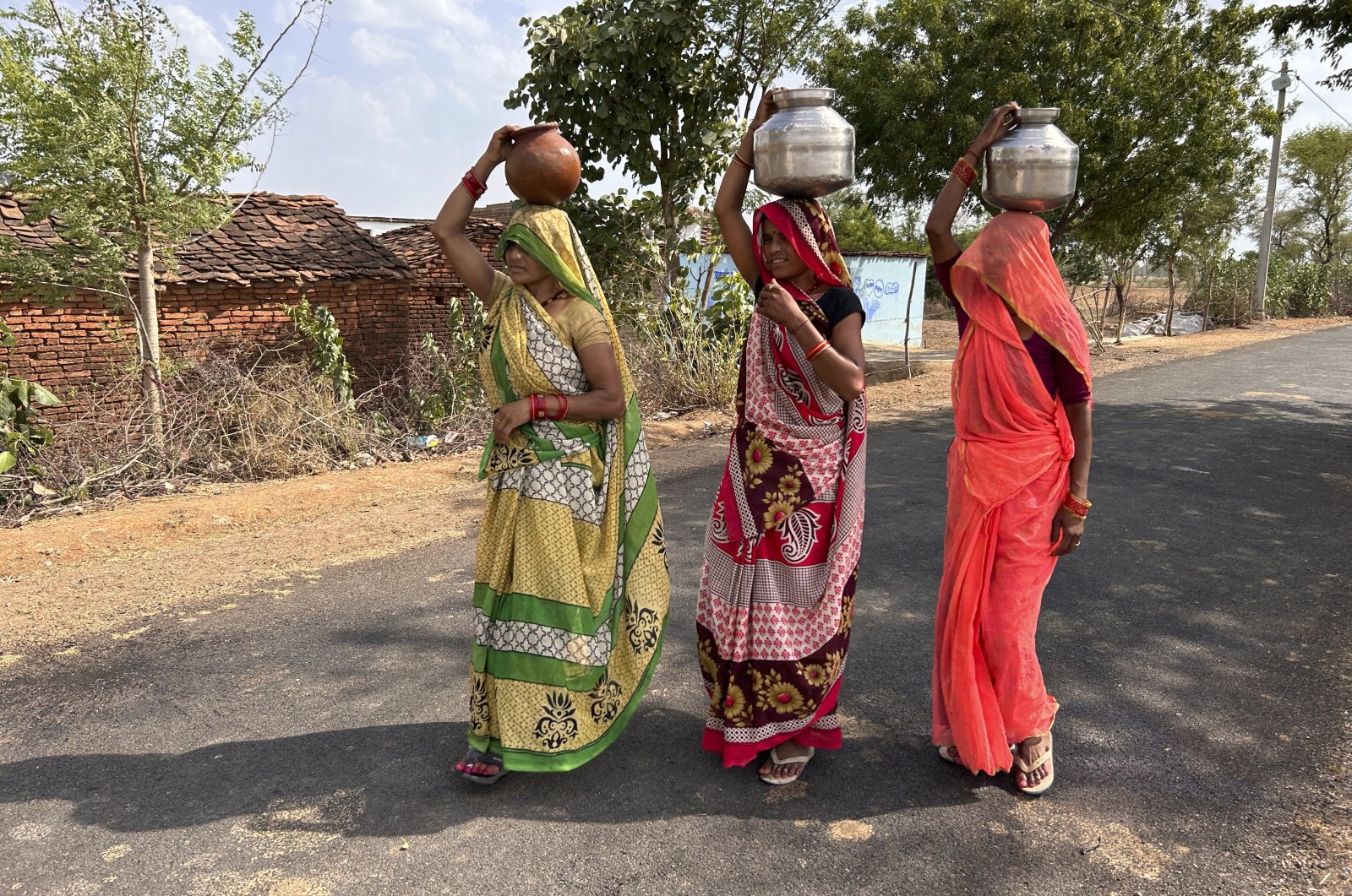 Women walk as they carry pitchers filled with drinking water on a hot summer afternoon in Lalitpur, Uttar Pradesh state, India, Saturday, June 17, 2023. (AP Photo)