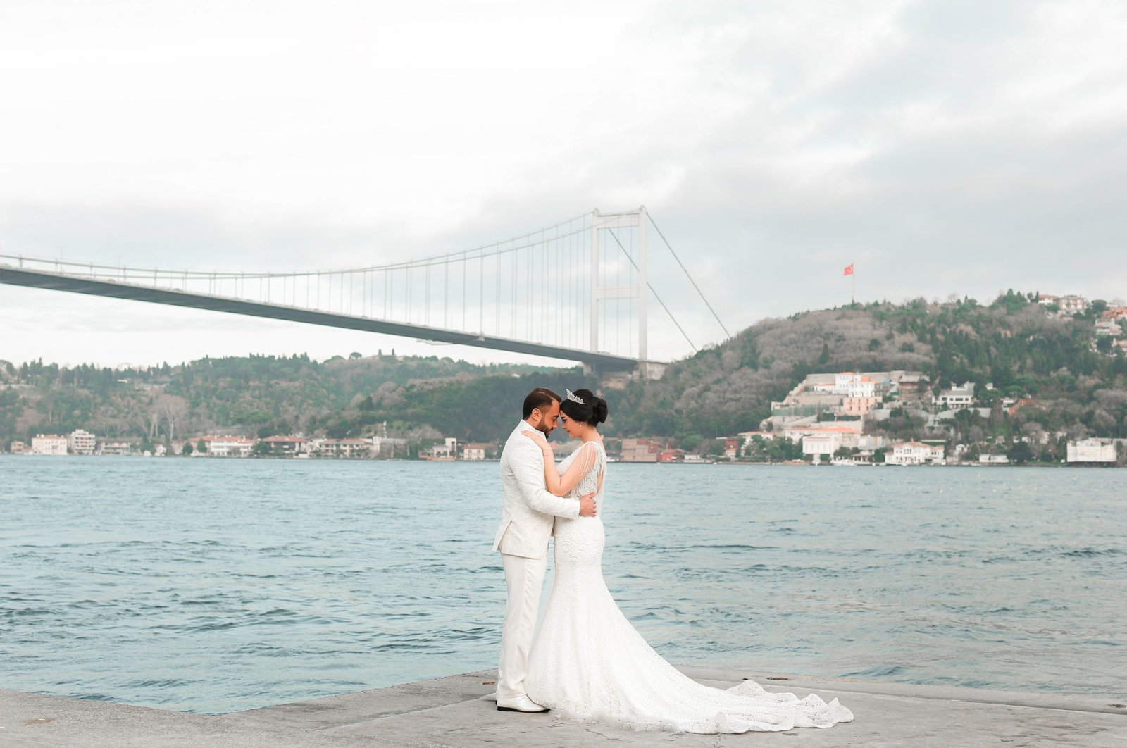 A newlywed couple poses with the Bosporus in the background, in Istanbul, Türkiye, Feb. 20, 2021. (Shutterstock Photo)