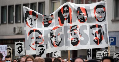 Demonstrators hold up a banner with images of the nine victims of Hanau attacks, in Hanau, Germany, Feb. 19, 2021. (AFP Photo)
