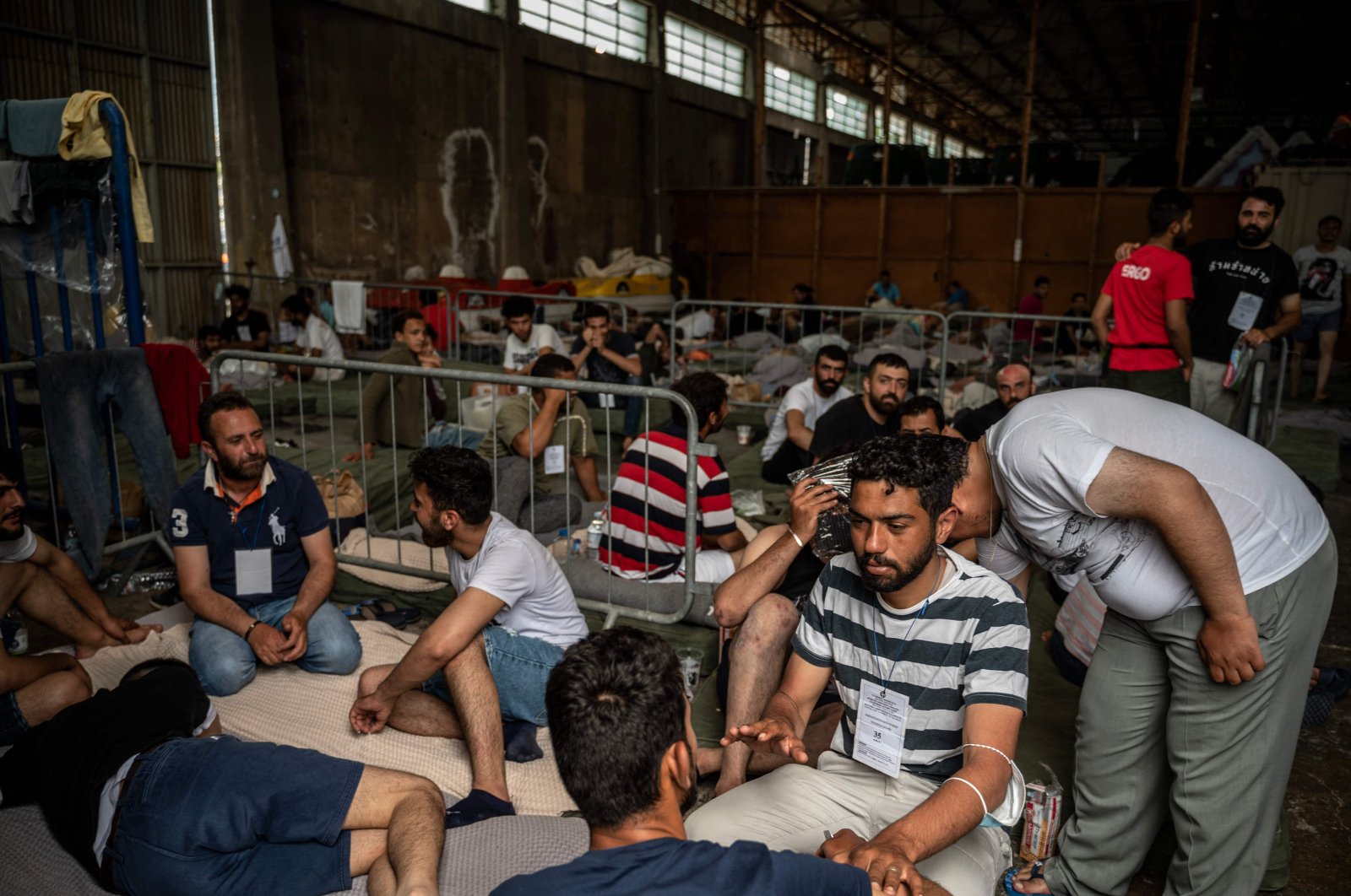 Survivors of a shipwreck sit inside a warehouse at the port in Kalamata town, Greece, June 15, 2023. (AFP Photo)