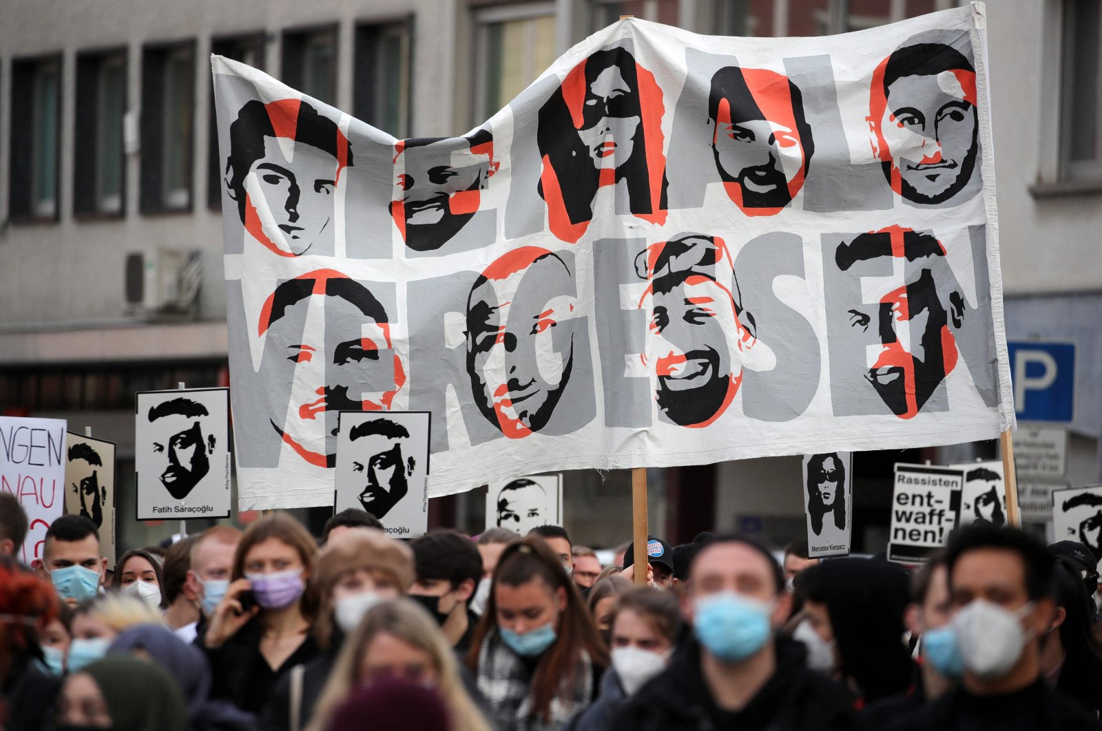 Demonstrators hold up a banner with images of the nine victims of Hanau attacks, in Hanau, Germany, Feb. 19, 2021. (AFP Photo)