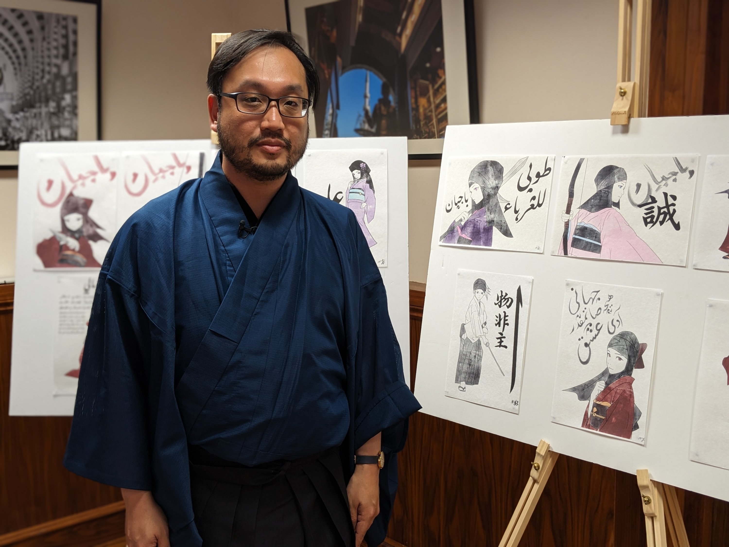 Qayyim Naoki Yamamoto poses with the calligraphy artworks, London, U.K., June 20, 2023. (Photo courtesy of YEE)