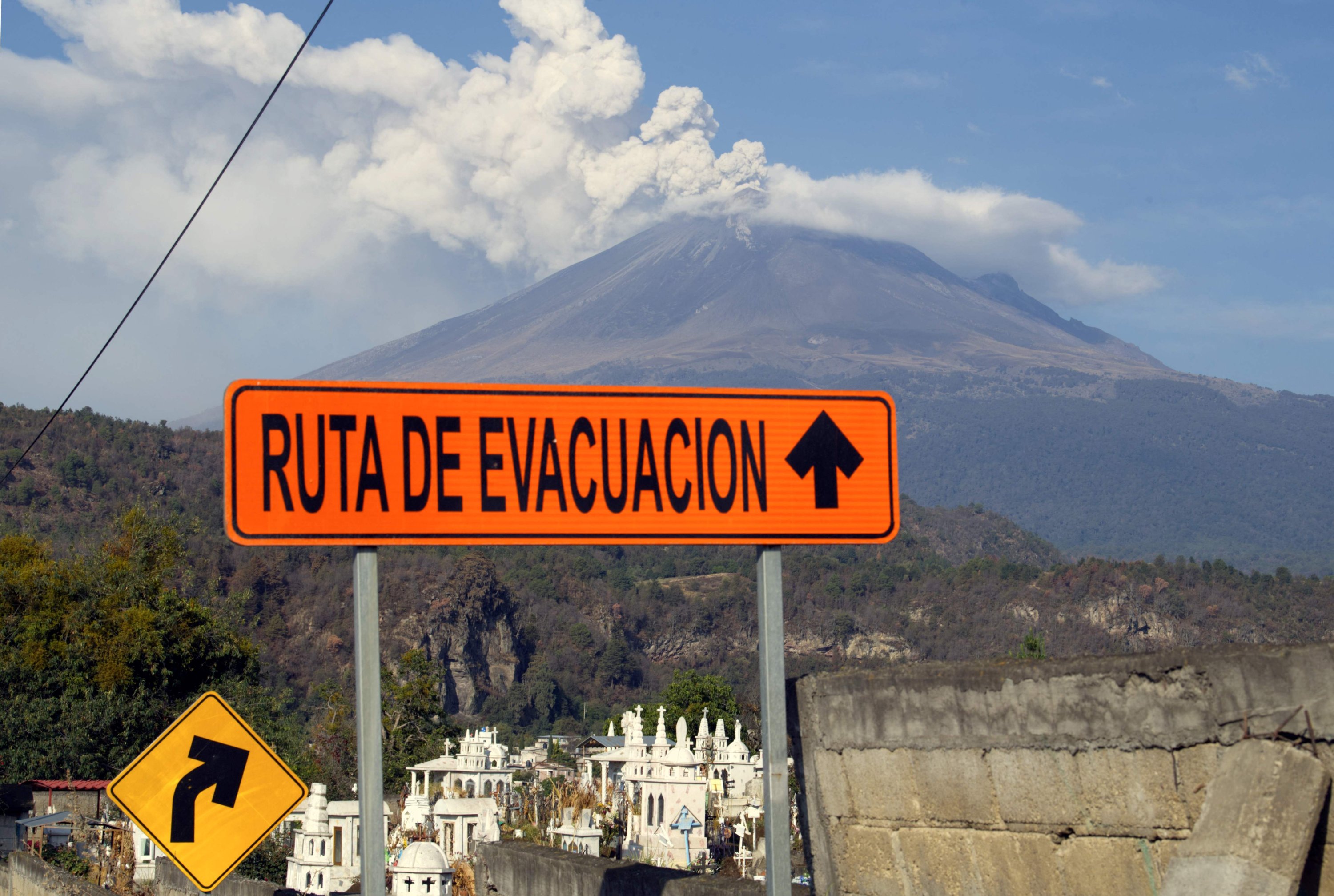 Pemandangan gunung berapi Popocatepetl dan tanda-tanda jalur evakuasi di Santiago Xalitzintla, negara bagian Puebla, Meksiko, 25 Mei 2023. (Foto AFP)
