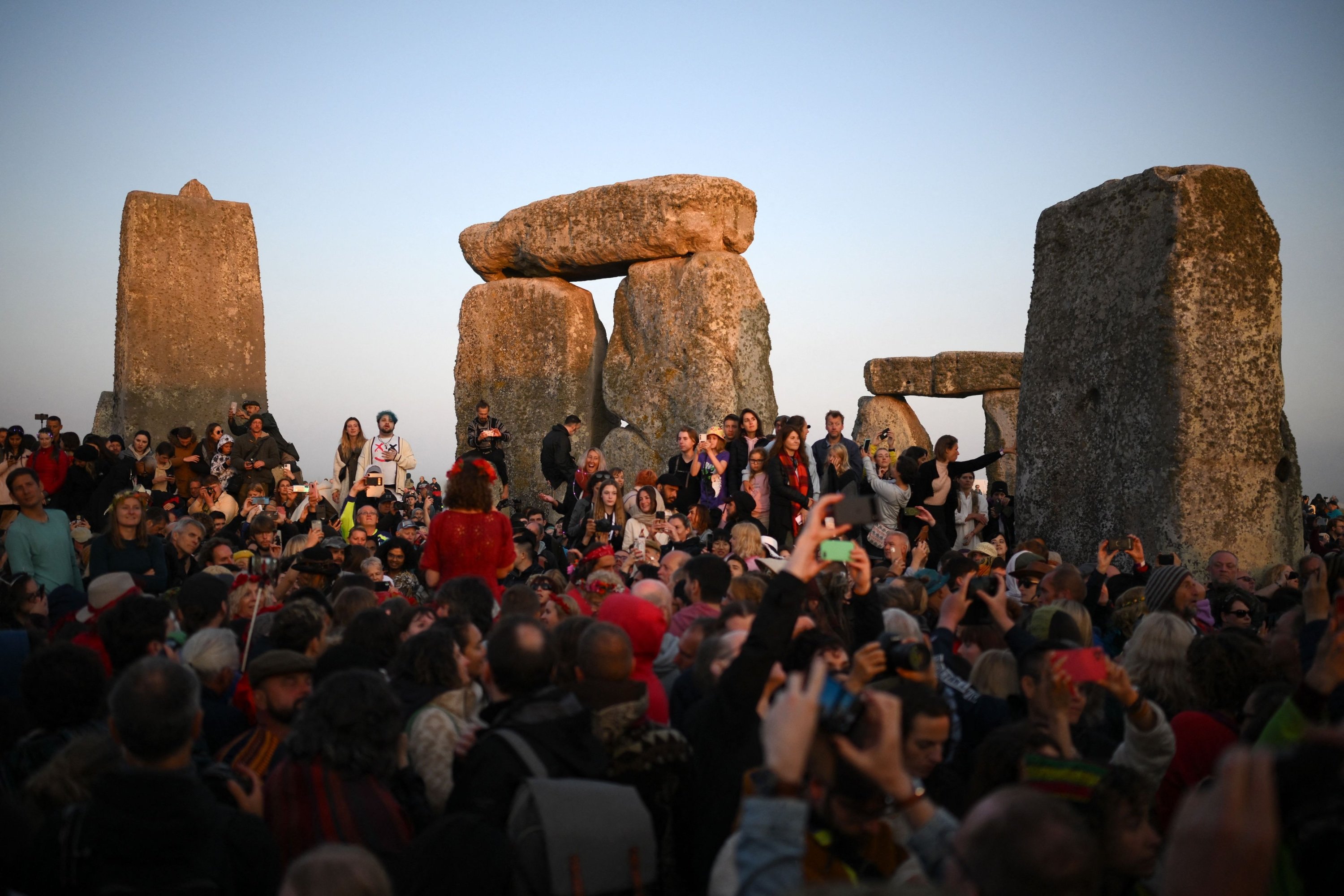 Orang-orang yang bersuka ria merayakan Summer Solstice saat matahari terbit di Stonehenge, dekat Amesbury, di Wiltshire, Inggris selatan, 21 Juni 2023. (AFP Photo)