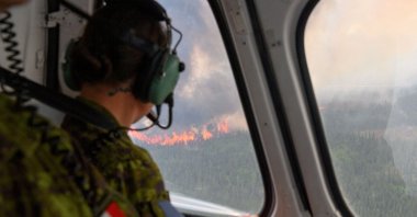 A soldier of the 5th Canadian Mechanized Brigade Group (5 CMBG) views a wildfire from a Canadian Forces helicopter surveying the area near Mistissini, Quebec, Canada June 12, 2023. (Canadian Forces/Handout via Reuters)