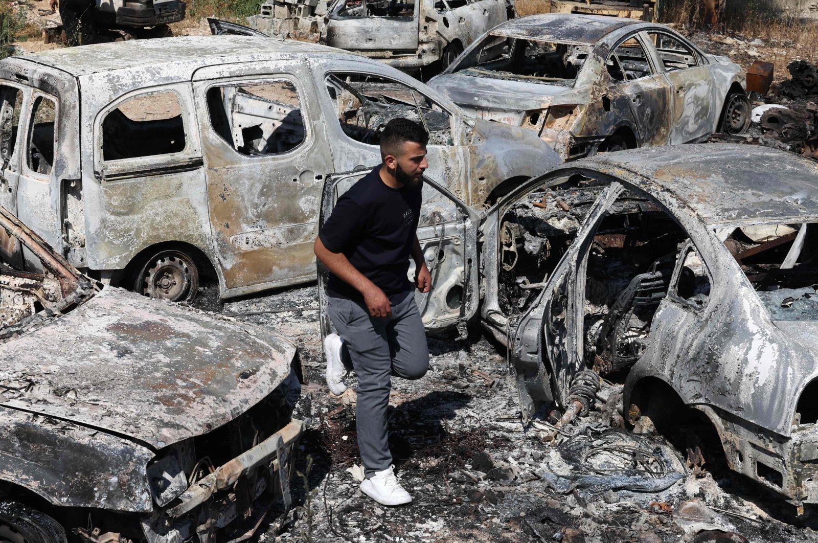 A man walks amid burnt cars, reportedly set ablaze by Israeli settlers, in the occupied West Bank, Palestine, June 21, 2023. (AFP Photo)
