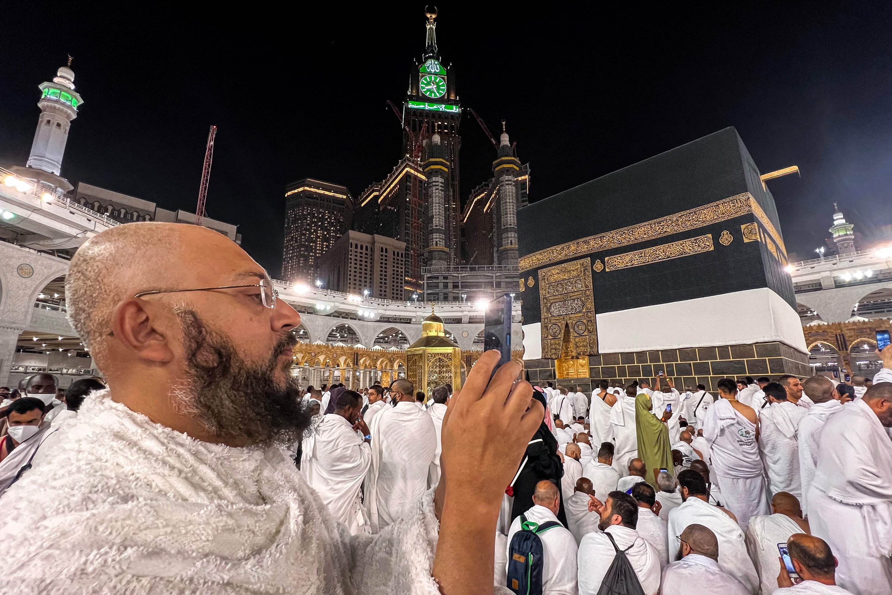 Seorang jamaah Muslim menggunakan ponselnya untuk memfilmkan saat dia berdiri di dekat Ka'bah, situs paling suci Islam, di Masjidil Haram di kota suci Mekkah, Arab Saudi, 22 Juni 2023. (AFP Photo)
