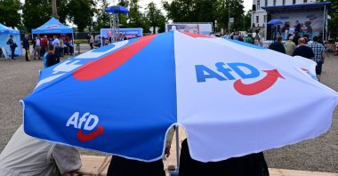 Far-right AfD supporters stand under an umbrella with the party&#039;s logo at a rally in Schwerin, Germany, August 10, 2021. (AFP Photo)