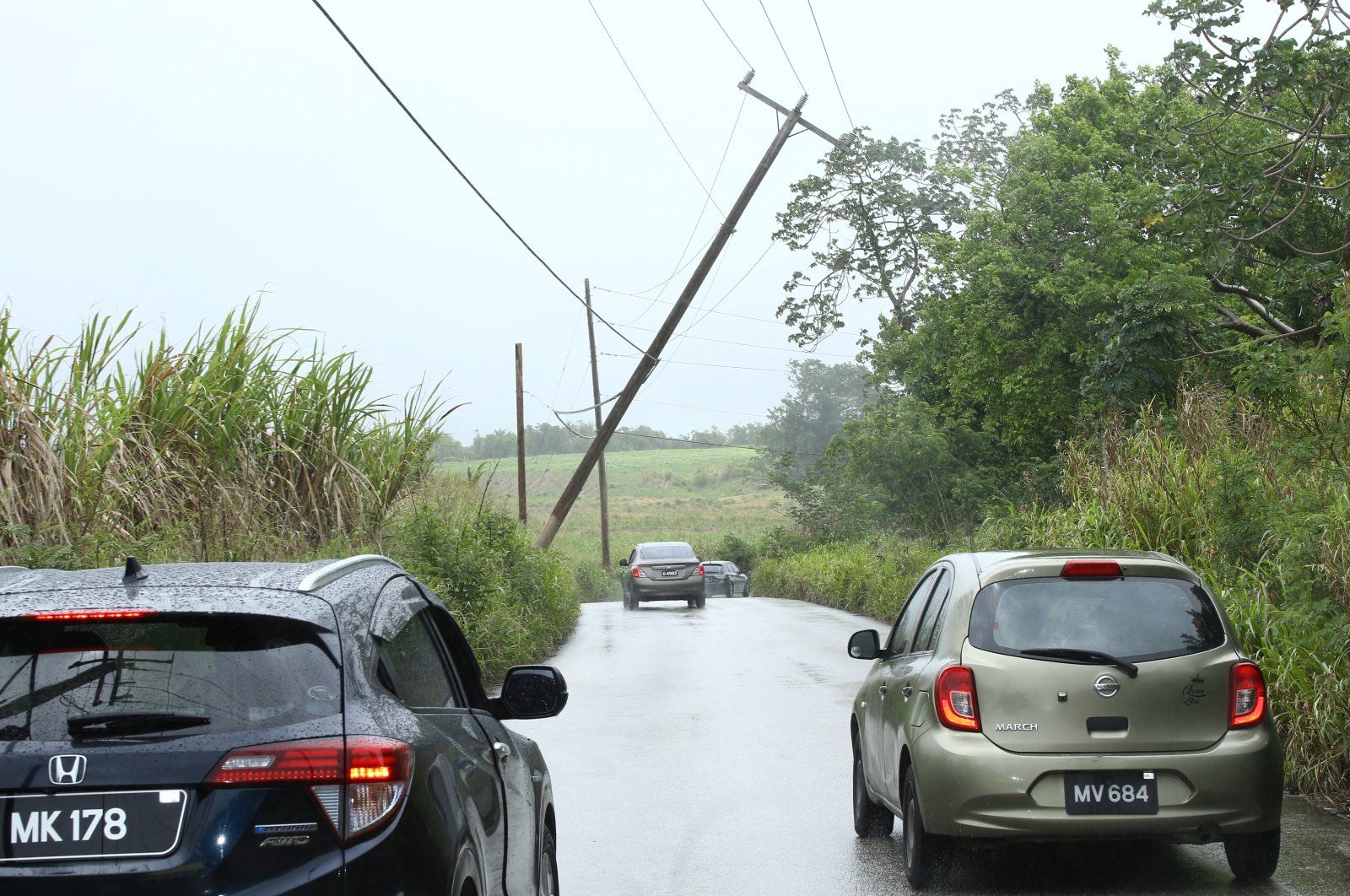 Cars pass a leaning power pole after Tropical Storm Bret passed north of the island, in St. Thomas, Barbados June 22, 2023. (Reuters Photo)