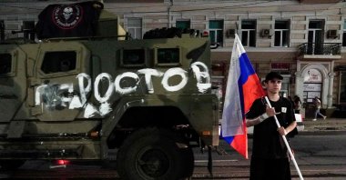 A man holds the Russian flag in front of a Wagner group military vehicle with the sign read as "Rostov" in Rostov-on-Don, Russia, June 24, 2023. (AFP Photo)