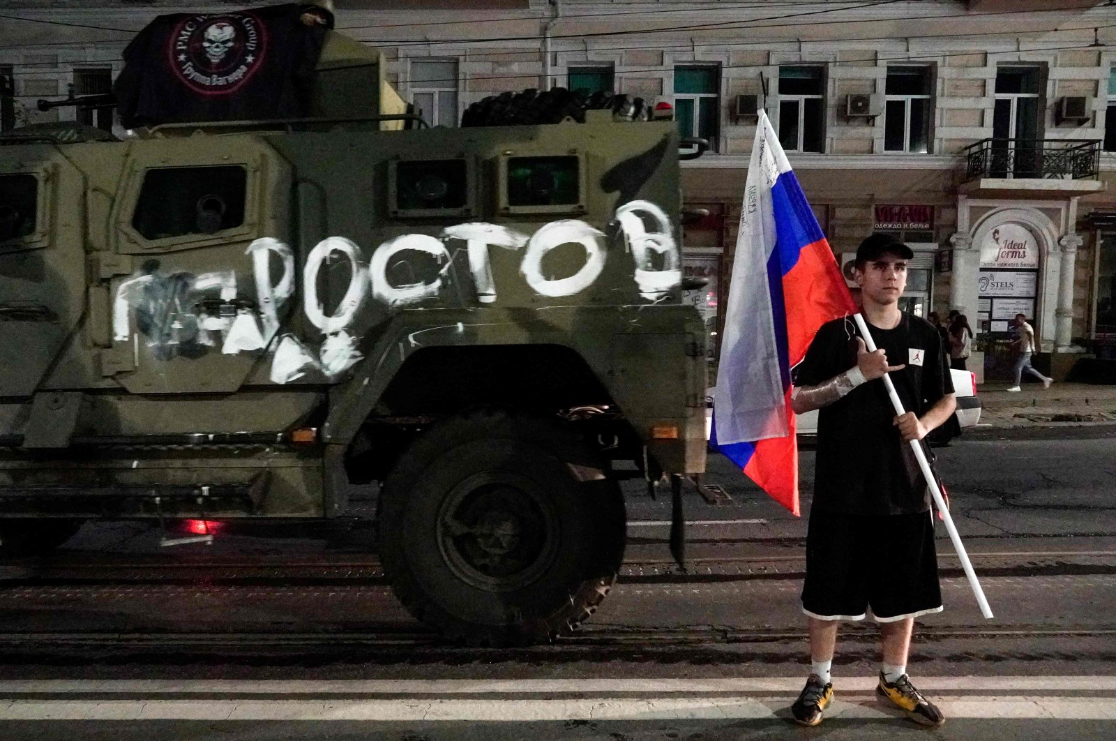 A man holds the Russian flag in front of a Wagner group military vehicle with the sign read as &quot;Rostov&quot; in Rostov-on-Don, Russia, June 24, 2023. (AFP Photo)