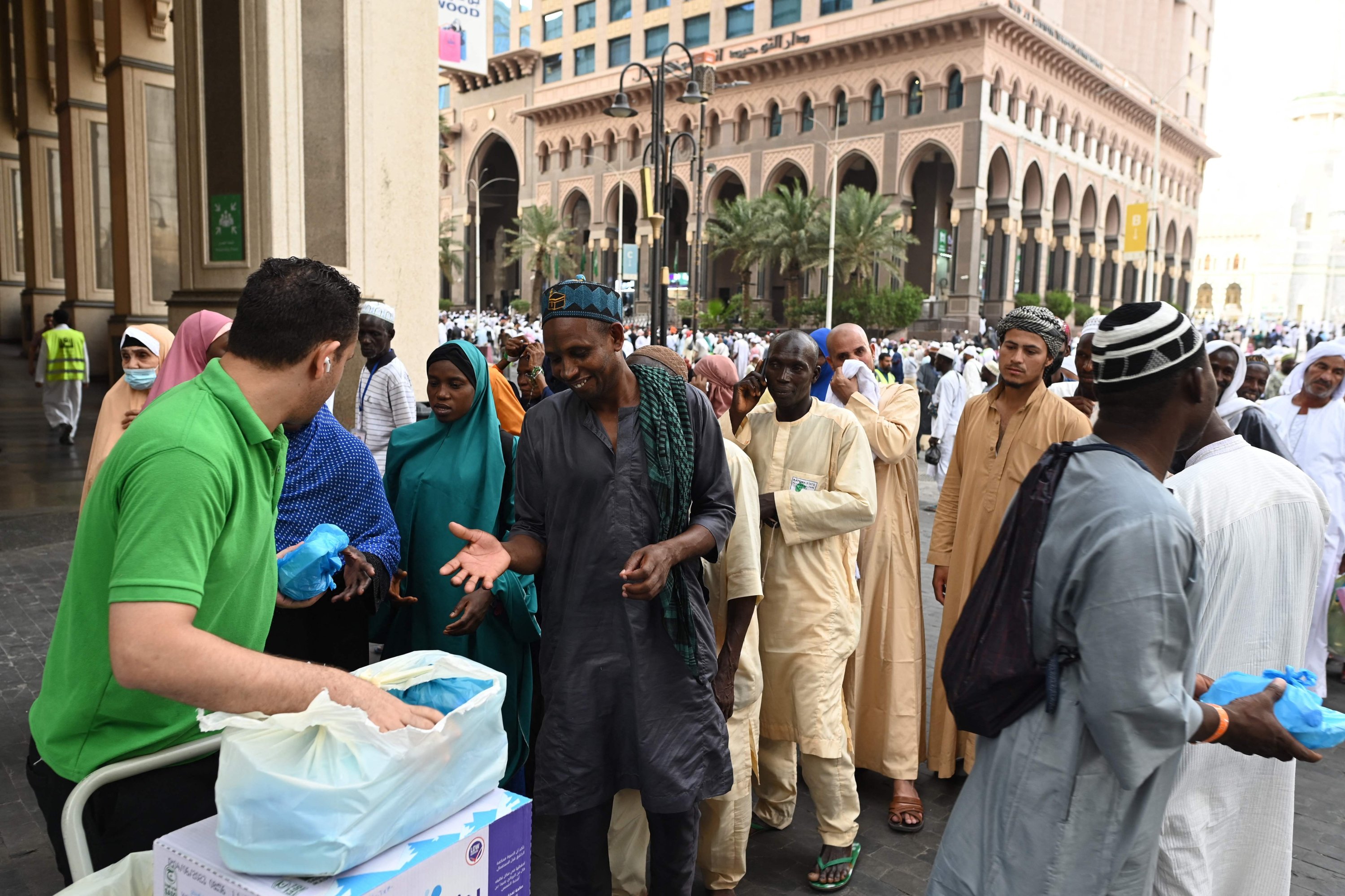Seorang relawan membagikan paket sembako yang dipersembahkan warga Mekkah kepada jemaah haji, Mekkah, Arab Saudi, 23 Juni 2023. (Foto AFP)
