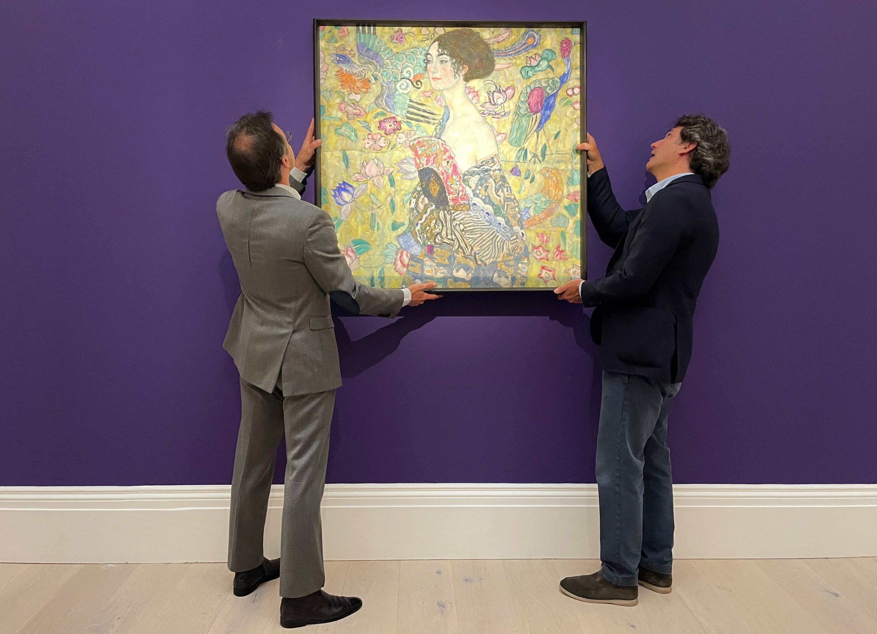 Karyawan berpose dengan karya seni berjudul 'Lady with a Fan' karya seniman Austria Gustav Klimt, saat sesi pemotretan di rumah lelang Sotheby di pusat kota London, Inggris, 20 Juni 2023. (Foto Reuters)