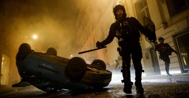 French riot police officers walk next to a vehicle upside down during the fifth day of protests in Paris, France, July 2, 2023. (Reuters Photo)