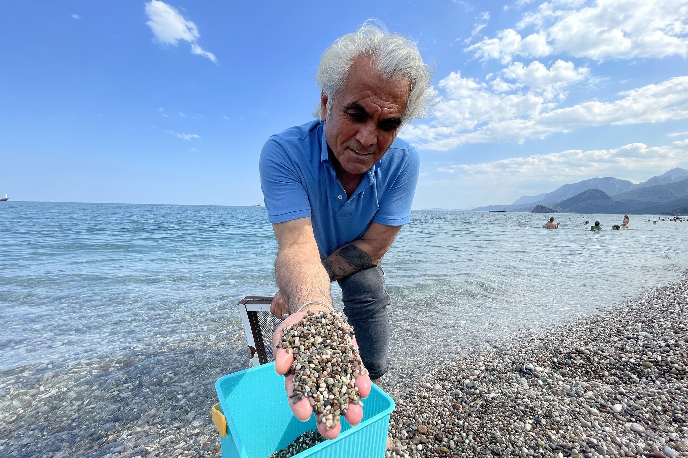 Artist Süleyman Sarı collects pebbles from the beach, in Antalya, Türkiye, July 2, 2023. (AA Photo)