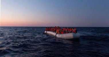 A Sea-Watch 3 crew member on a lifeboat approaches an inflatable boat with 120 people on board in the central Mediterranean, July 23, 2022. (Handout by Sea-Watch AFP Photo)