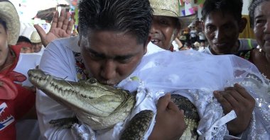 San Pedro Huamelula Mayor Victor Hugo Sosa kisses a spectacled caiman before marrying her in San Pedro Huamelula, Oaxaca state, Mexico, June 30, 2023. (AFP Photo)