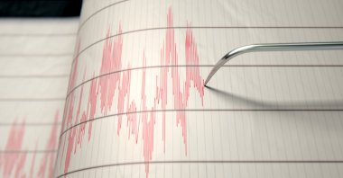 A closeup of a seismograph machine needle drawing a red line on graph paper depicting seismic and earthquake activity in this undated file photo. (Shutterstock File Photo)