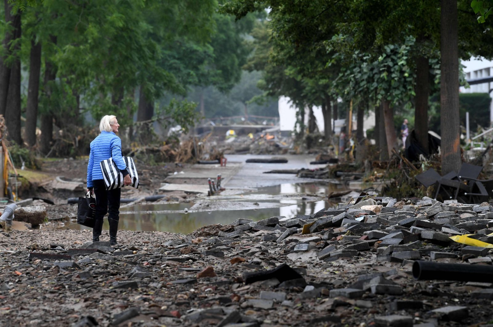 A woman carries bags in a devastated street after floods caused major damage in Bad Neuenahr-Ahrweiler, western Germany, July 16, 2021. (AFP Photo)