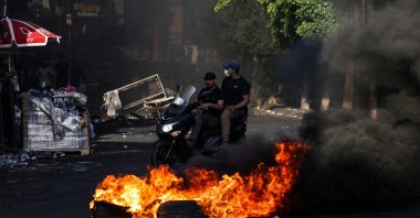 Men ride a motorcycle past a fire amidst clashes between Palestinians and the Israeli army in the occupied West Bank city of Jenin on July 4, 2023. (AFP Photo)