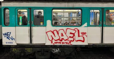 Commuters ride on a metro train bearing graffiti reading &quot;Nael, Rest in Peace&quot; Paris, France, July 4, 2023. (AFP Photo)