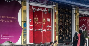Women walk past a beauty salon at the Shahr-e Naw area in Kabul, July 4, 2023. (AFP Photo)