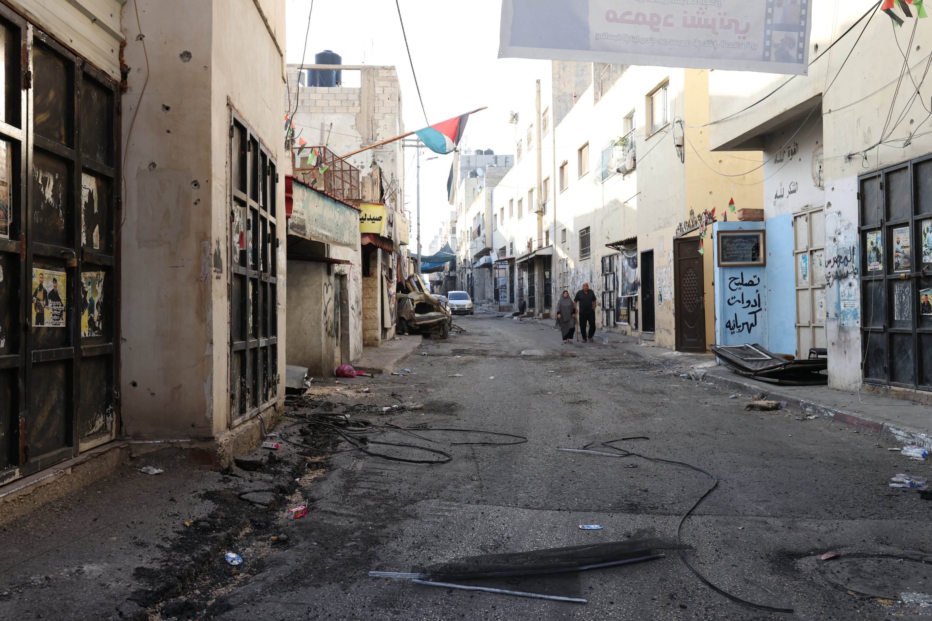 Warga Palestina berjalan di jalan yang rusak, setelah serangan tentara Israel di Jenin, Tepi Barat, 5 Juli 2023. (Foto EPA)