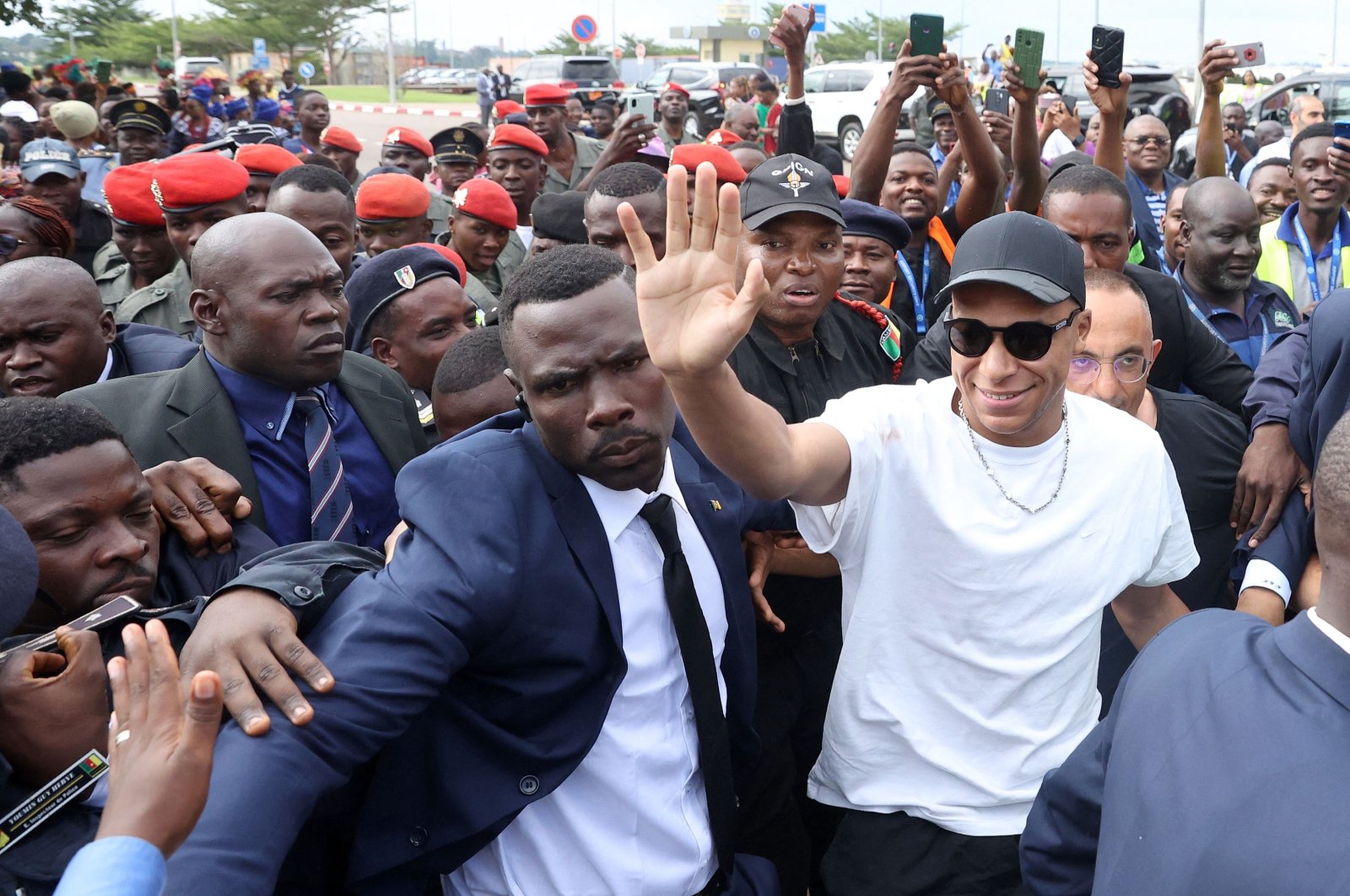 Paris Saint-Germain and France national football team star striker Kylian Mbappe (C-R) greets crowds gathered outside at the Yaounde Airport as he arrives for a charity visit and a tour of his father&#039;s village, Yaounde, Cameroon, July 6, 2023. (AFP Photo)