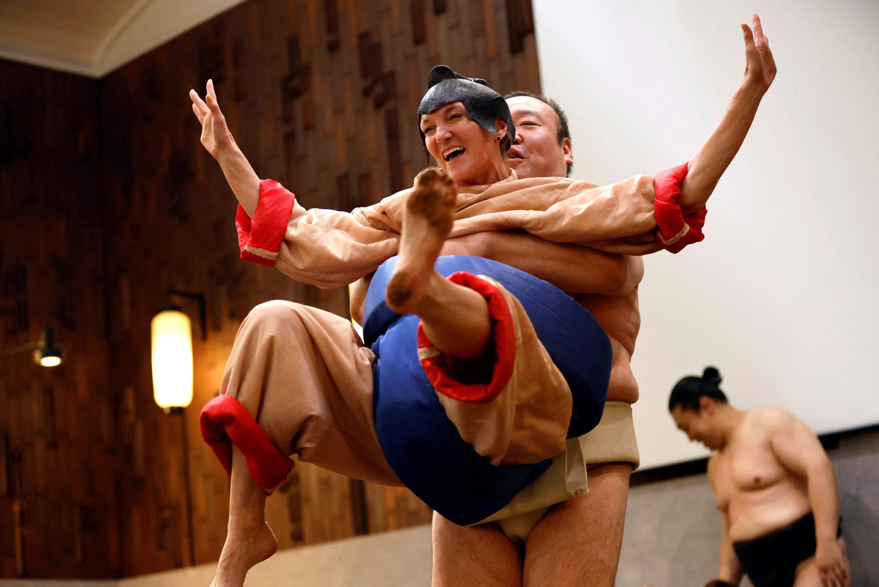 Nadine, seorang turis berusia 43 tahun dari AS, mengenakan kostum pegulat sumo, mencoba bertanding melawan mantan pegulat sumo Towanoyama di ring sumo di depan turis dari luar negeri, Tokyo, Jepang, 30 Juni 2023. (Foto Reuters)