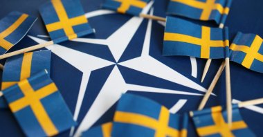In this photo taken in Sweden's Motala on May 17, 2022, the Swedish national flags encircle the symbol of NATO. (Shutterstock Photo)