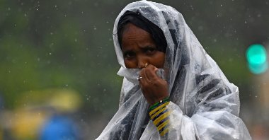 A woman uses a plastic sheet to protect herself from rain in New Delhi, India, July 10, 2023. (AFP Photo)