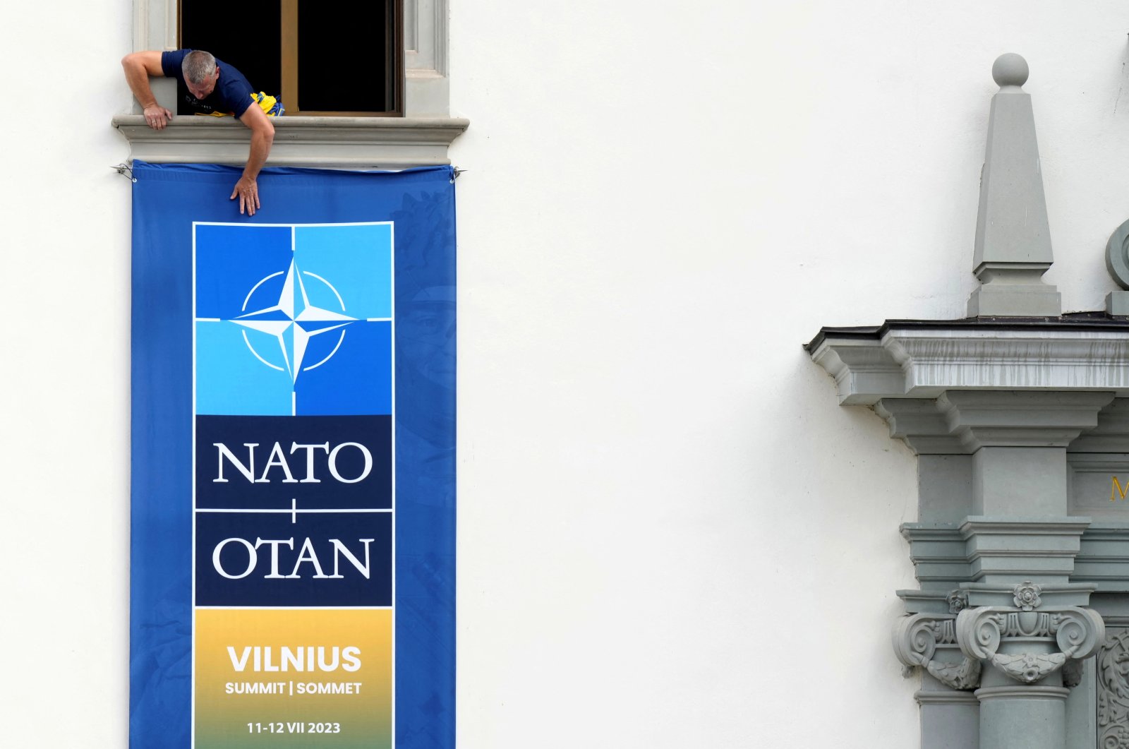 A worker installs a NATO summit banner on the wall of the Palace of the Grand Dukes of Lithuania in Vilnius, Lithuania, July 10, 2023. (Reuters Photo)