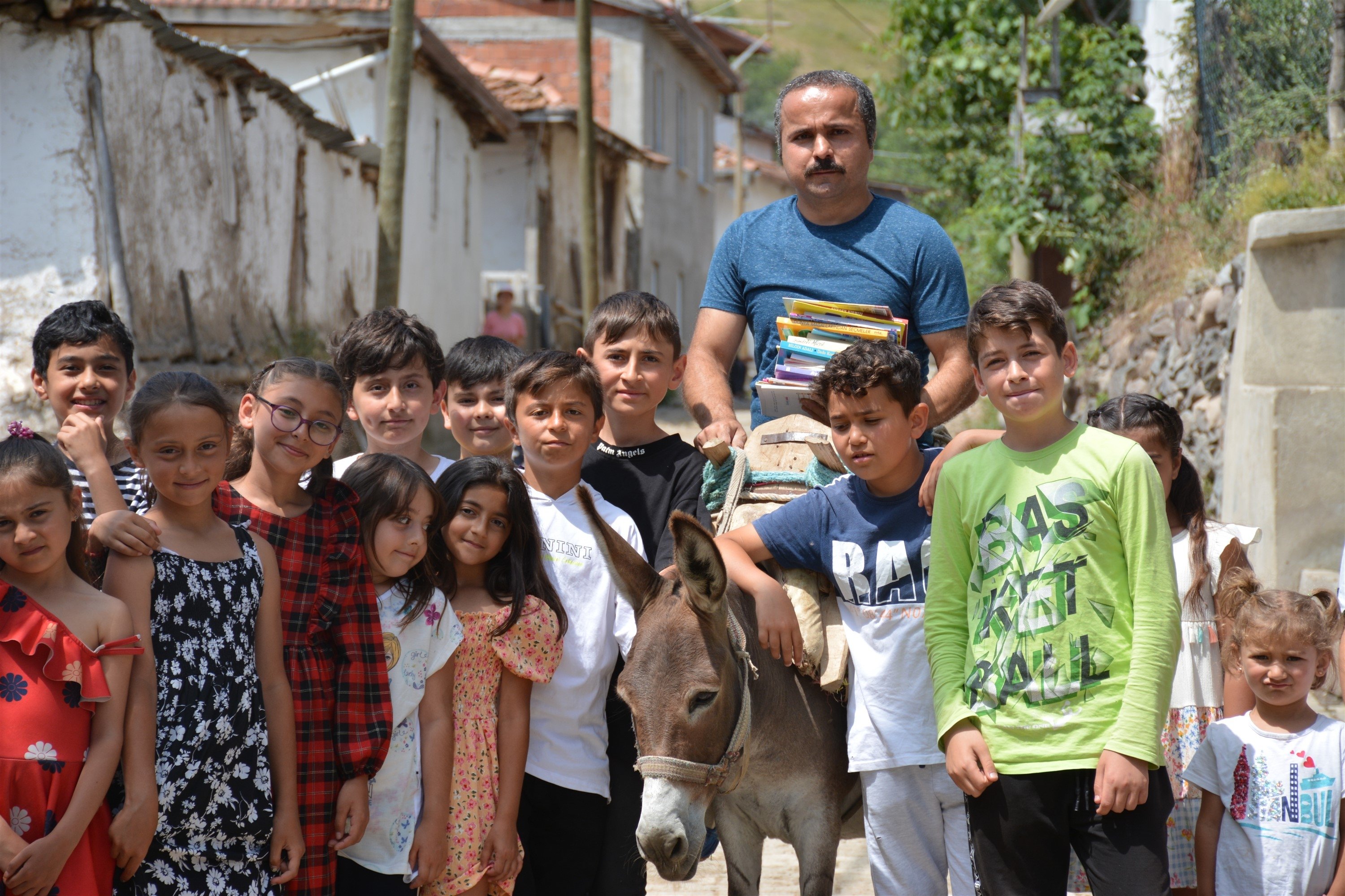 Metin Uğur berpose dengan buku tentang keledai dan anak-anaknya di Karacaören, Tokat, Türkiye, 11 Juli 2023. (Foto DHA)