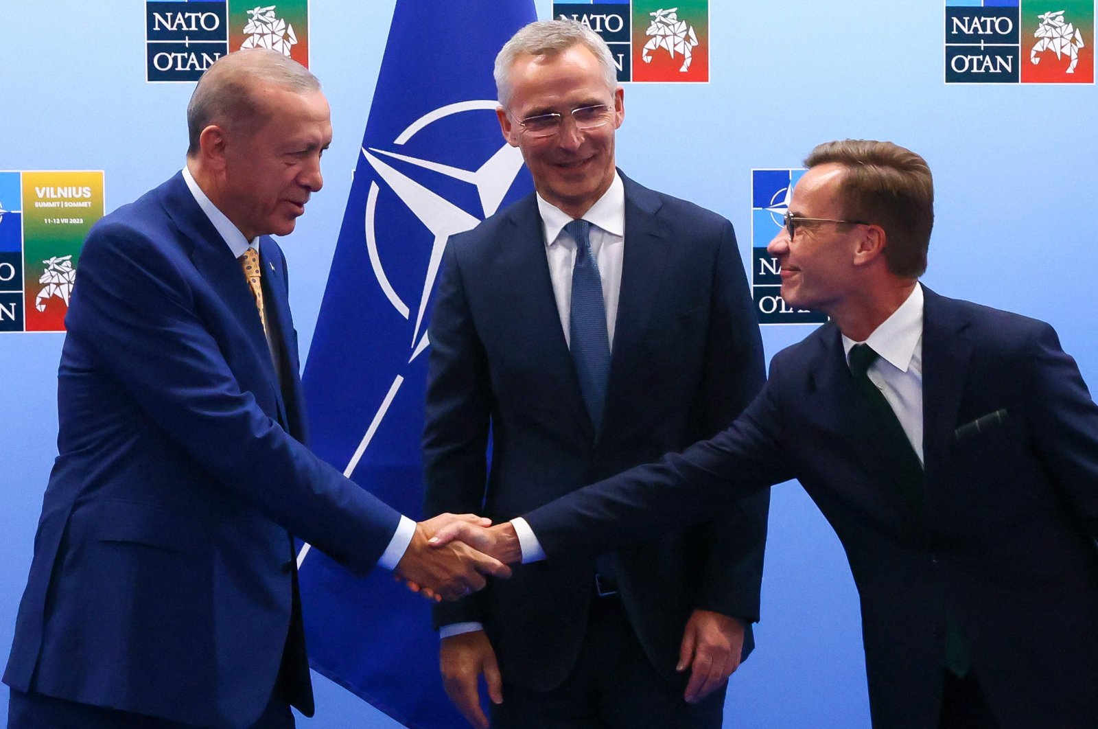 President Recep Tayyip Erdoğan (L) and Swedish Prime Minister Ulf Kristersson (R) shake hands in front of NATO Secretary-General Jens Stoltenberg (C) prior to their meeting, on the eve of a NATO summit, Vilnius, Lithuania, July 10, 2023. (AFP Photo)