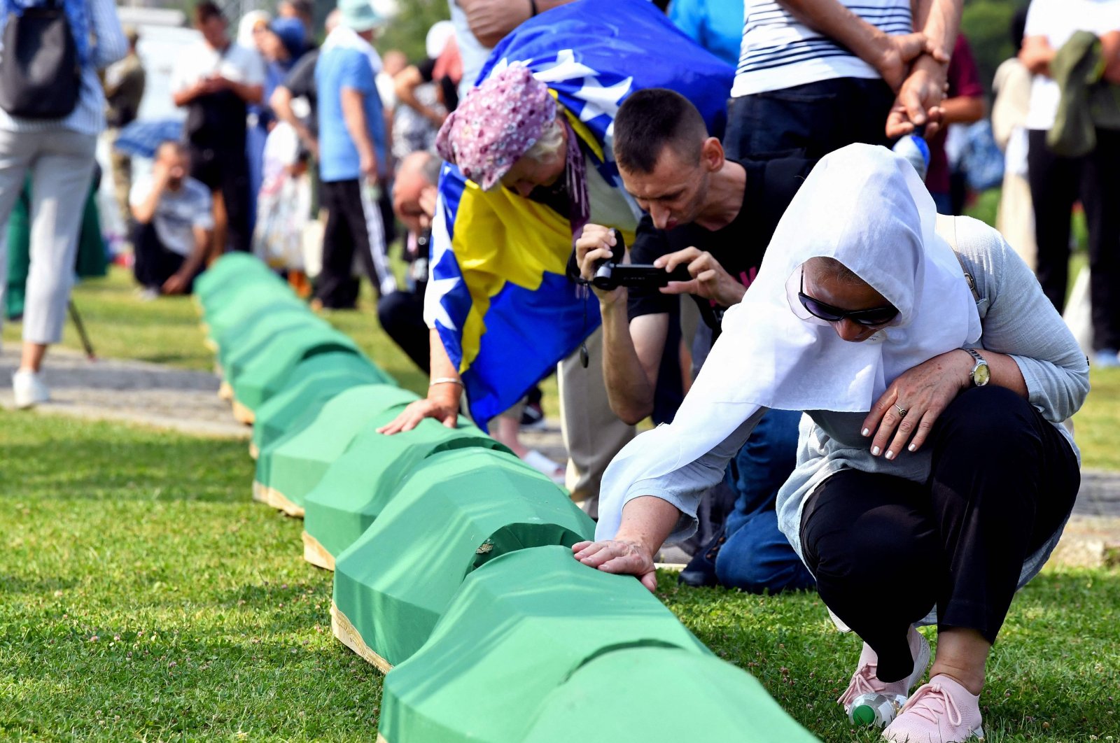 A Bosnian Muslim woman, survivor of the Srebrenica 1995 massacre mourns near the casket containing the remains of a relative and victim of the Srebrenica 1995 massacre, at the memorial cemetery in the village of Potocari, near Eastern-Bosnian town of Srebrenica, on July 11, 2023. (AFP Photo)