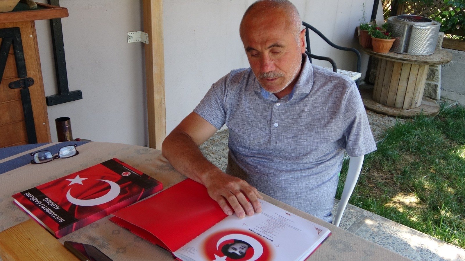 Üzeyir Civan looks at an album about people killed and shot by putschists, in his home, in Istanbul, Türkiye, July 12, 2023. (İHA Photo) 