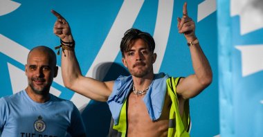 Manchester City&#039;s English midfielder Jack Grealish (R) celebrates next to Manchester City&#039;s Spanish manager Pep Guardiola (L) on stage following an open-top bus victory parade for their European Cup, FA Cup and Premier League victories, Manchester, U.K., June 12, 2023. (AFP Photo)