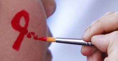 A woman gets her face painted with a red ribbon during a World AIDS Day awareness campaign, Kuala Lumpur, Malaysia, Dec. 1, 2012. (AP Photo)