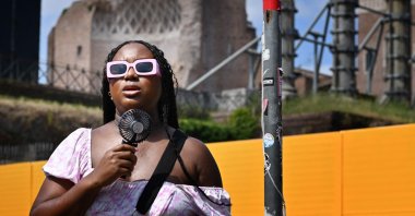 A woman cools off with a mini fan  in Rome, on July 14, 2023, as Italy is hit by a heatwave. (Photo by Alberto PIZZOLI / AFP)