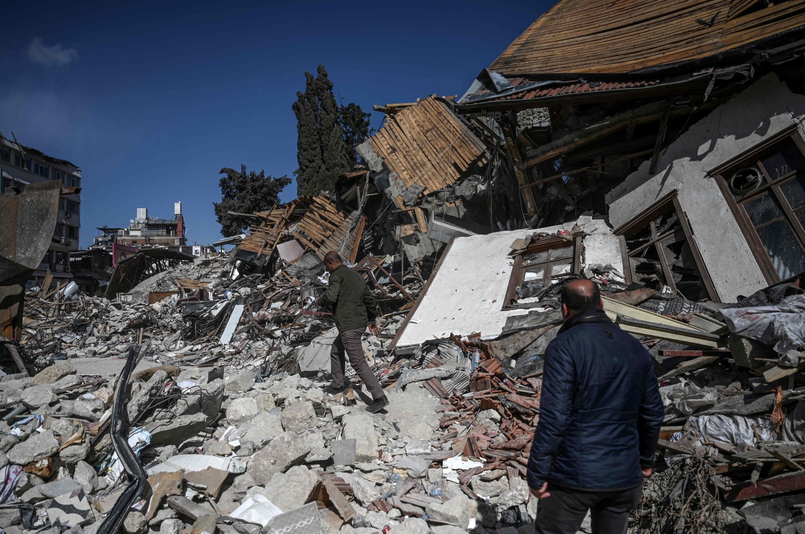 People walk among the rubble of collapsed buildings after massive earthquakes in Hatay, southeastern Türkiye, March 6, 2023. (AFP Photo)