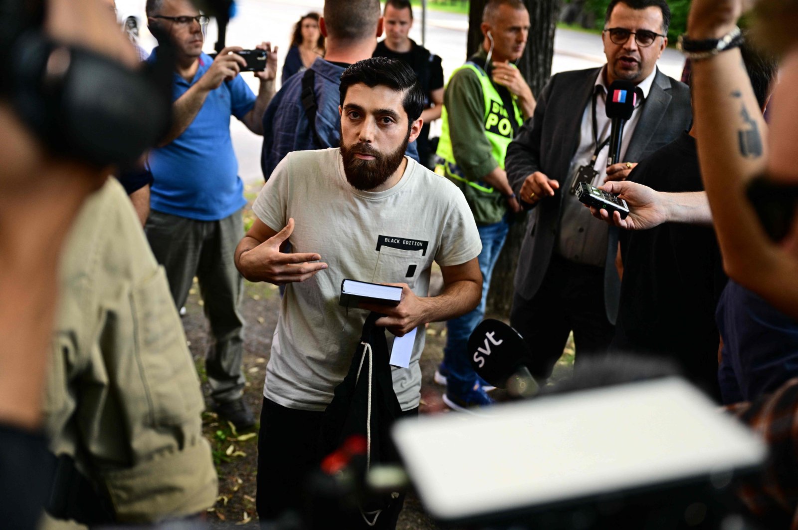 Ahmad A. (C) who has been given permission by the police for a public gathering to burn a Torah and a Bible outside the Israeli embassy in Stockholm, Sweden, is surrounded by journalists on July 15, 2023. (AFP Photo)