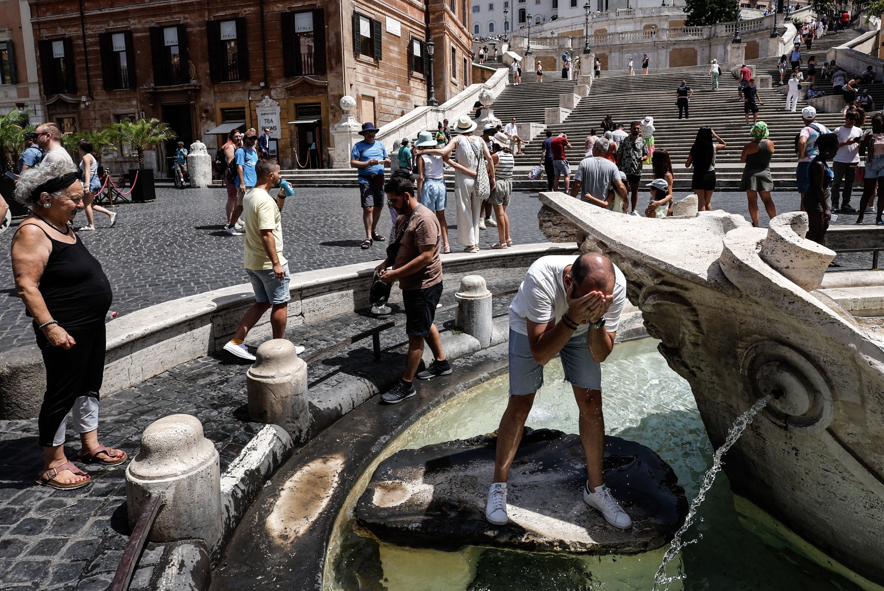 Orang-orang mendinginkan diri di sekitar air mancur di tengah suhu tinggi di Roma, Italia, 17 Juli 2023.