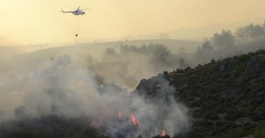 A helicopter is seen extinguishing a fire over the forests in Çanakkale, Türkiye, July 18, 2023. (IHA Photo)