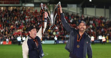 Wrexham owners Rob McElhenney and Ryan Reynolds (R) hold the Vanarama National League Trophy as Wrexham celebrate promotion back to the English Football League during the Vanarama National League match between Wrexham and Boreham Wood at Racecourse Ground, Wrexham, Wales, U.K., April 22, 2023. (Getty Images Photo)