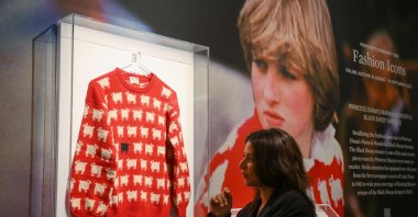 A staff member poses with the "Black Sheep Jumper" designed by Sally Muir and Joanna Osborne and worn on several occasions by Britain's late Princess Diana during a press view at Sotheby's auction house in London, U.K., July 17, 2023. (AFP Photo)