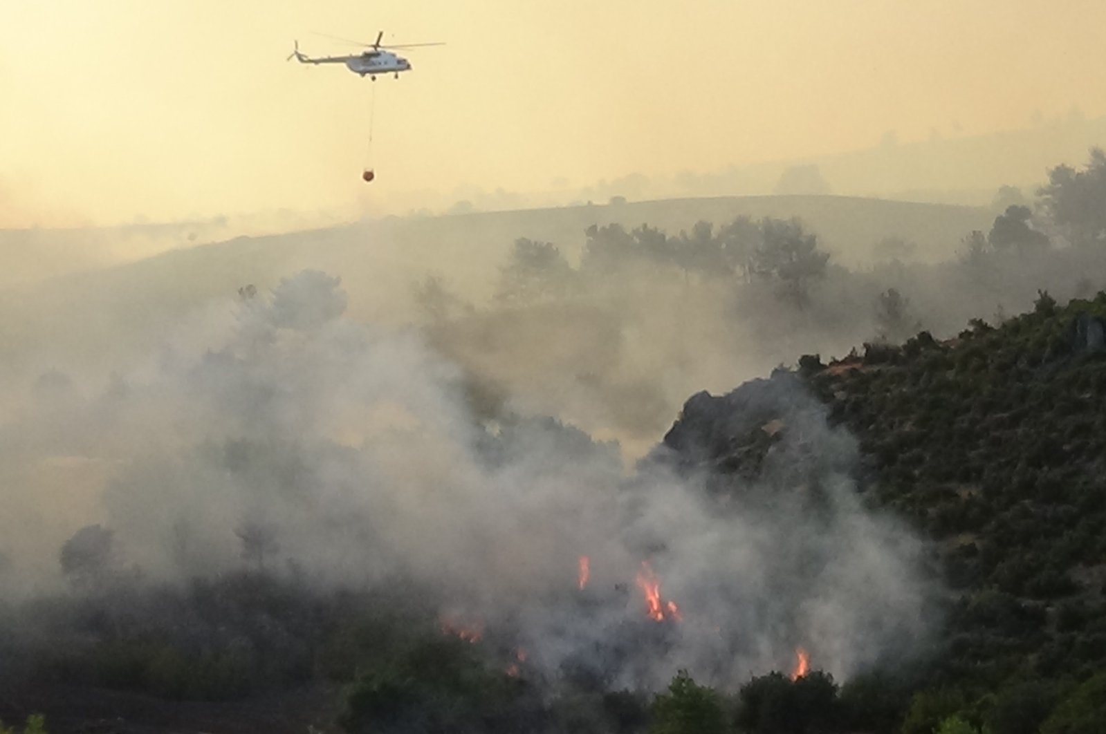 A helicopter is seen extinguishing a fire over the forests in Çanakkale, Türkiye, July 18, 2023. (IHA Photo)