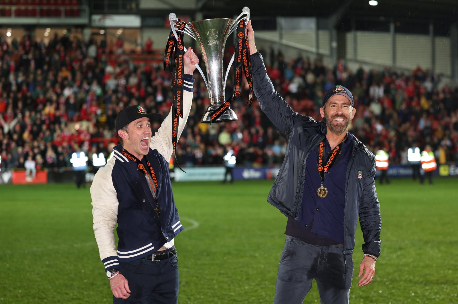 Wrexham owners Rob McElhenney and Ryan Reynolds (R) hold the Vanarama National League Trophy as Wrexham celebrate promotion back to the English Football League during the Vanarama National League match between Wrexham and Boreham Wood at Racecourse Ground, Wrexham, Wales, U.K., April 22, 2023. (Getty Images Photo)