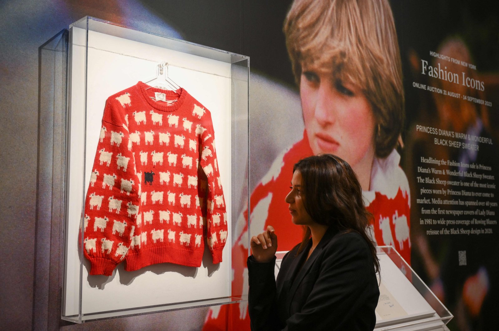A staff member poses with the &quot;Black Sheep Jumper&quot; designed by Sally Muir and Joanna Osborne and worn on several occasions by Britain&#039;s late Princess Diana during a press view at Sotheby&#039;s auction house in London, U.K., July 17, 2023. (AFP Photo)