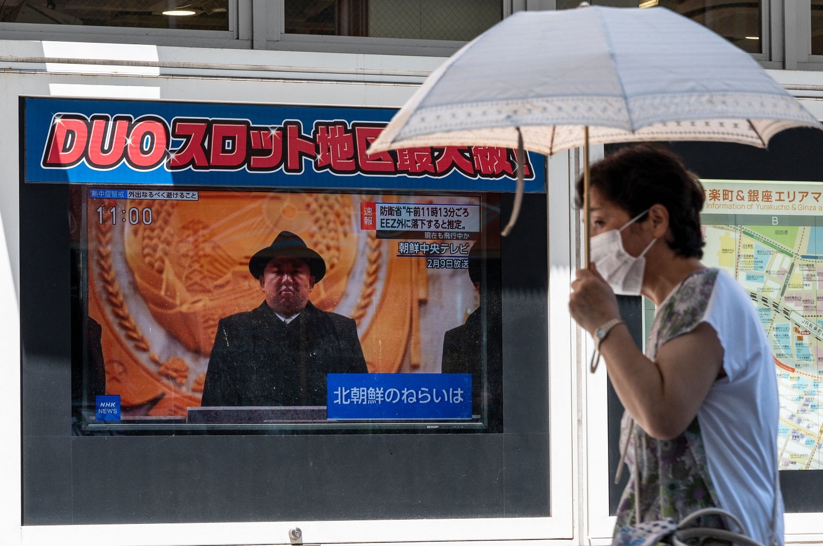 A woman shelters from the sun as she walks past a television news report about a North Korean missile launch that landed outside of Japan&#039;s exclusive economic zone west of the country, along a pedestrian walkway in downtown Tokyo on July 12, 2023. (AFP File Photo)