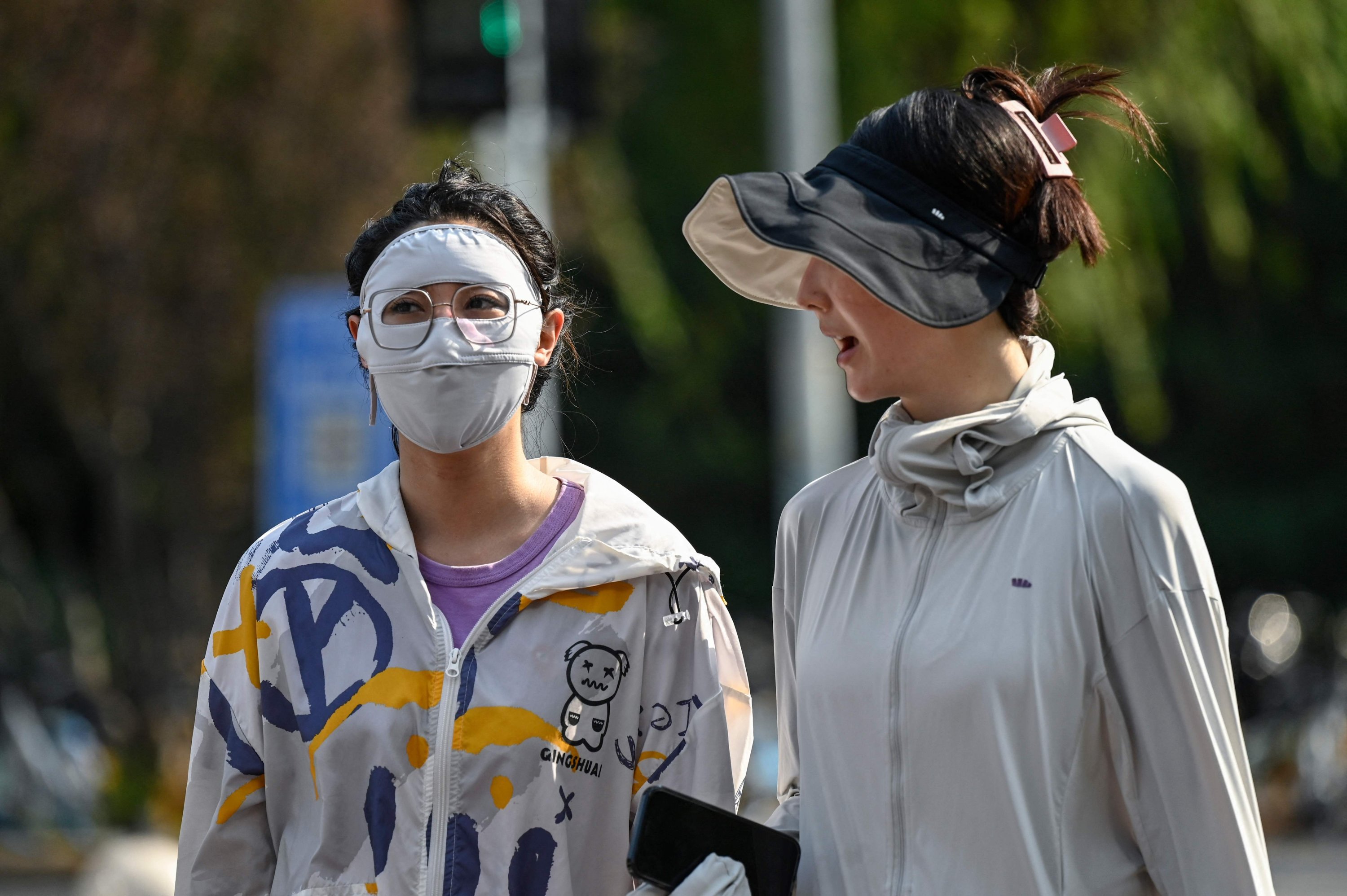 Seorang wanita mengenakan masker untuk berlindung dari sinar matahari di Beijing, China, 19 Juli 2023. (Foto AFP)